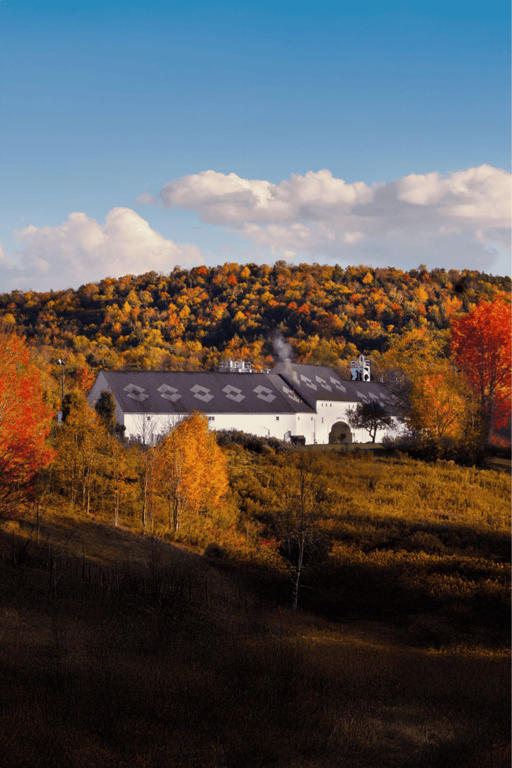 Autumn barn surrounded by colorful fall foliage and rolling hills, scenic rural landscape.
