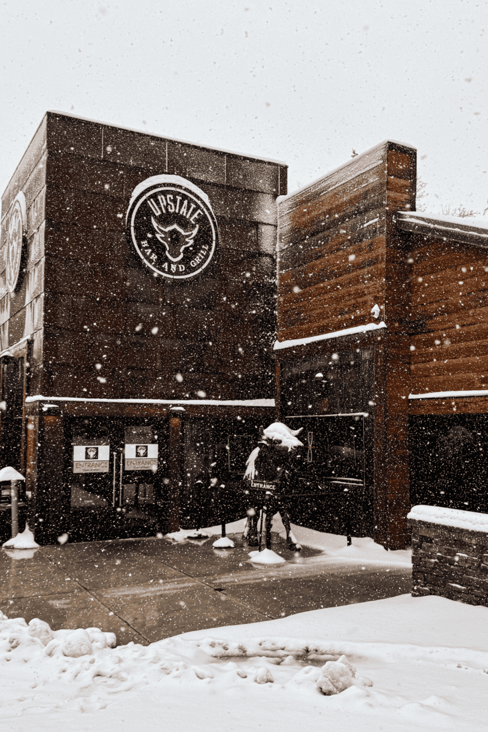 Cold weather winter scene at Quest for Directions restaurant, snow falling on building exterior.
