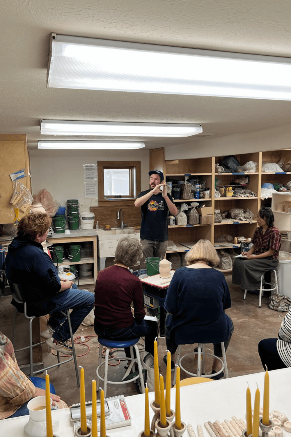 1. Indoor workshop with group of people learning pottery techniques.