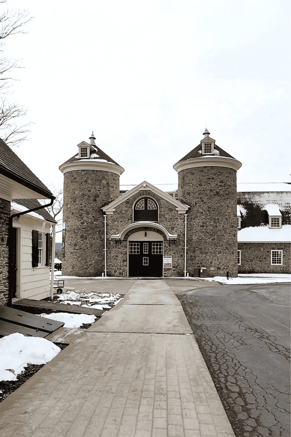 Stone castle-style buildings with turrets, snow on the ground, and a paved walkway leading to the entrance.