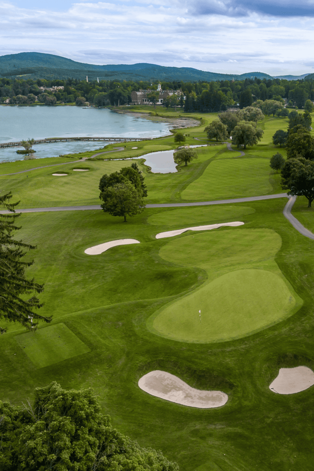 Golf course with scenic water views and lush greenery in a mountain setting.