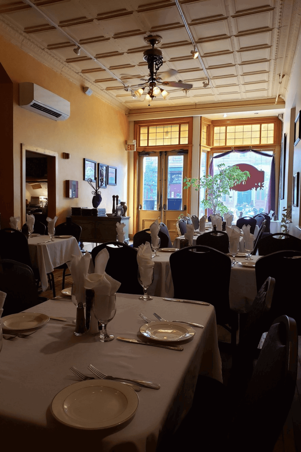 Cozy restaurant interior with elegant table settings and large front windows, ideal for dining and special occasions.
