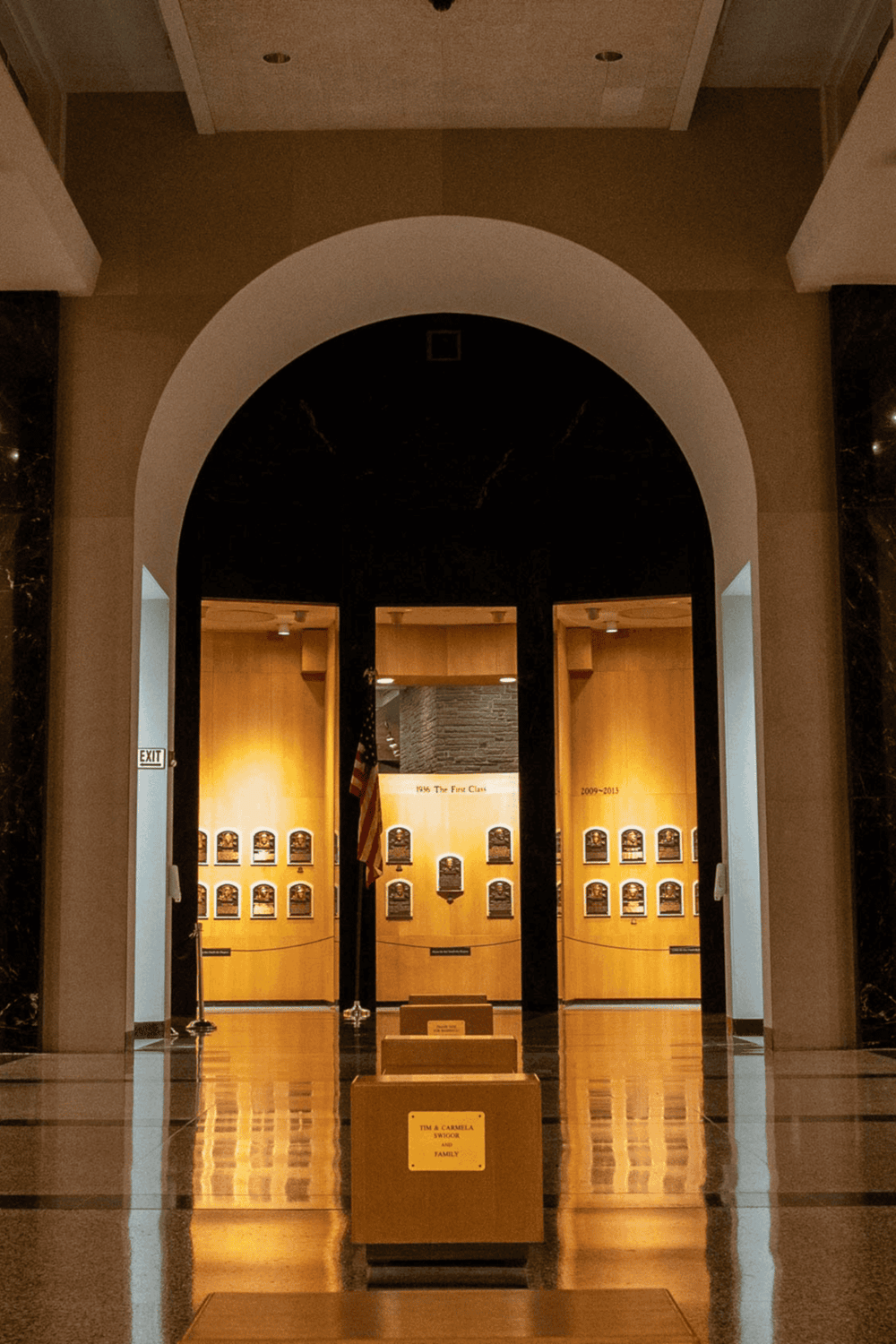 Memorial wall at QuestForDirections museum with historical plaques and American flag.