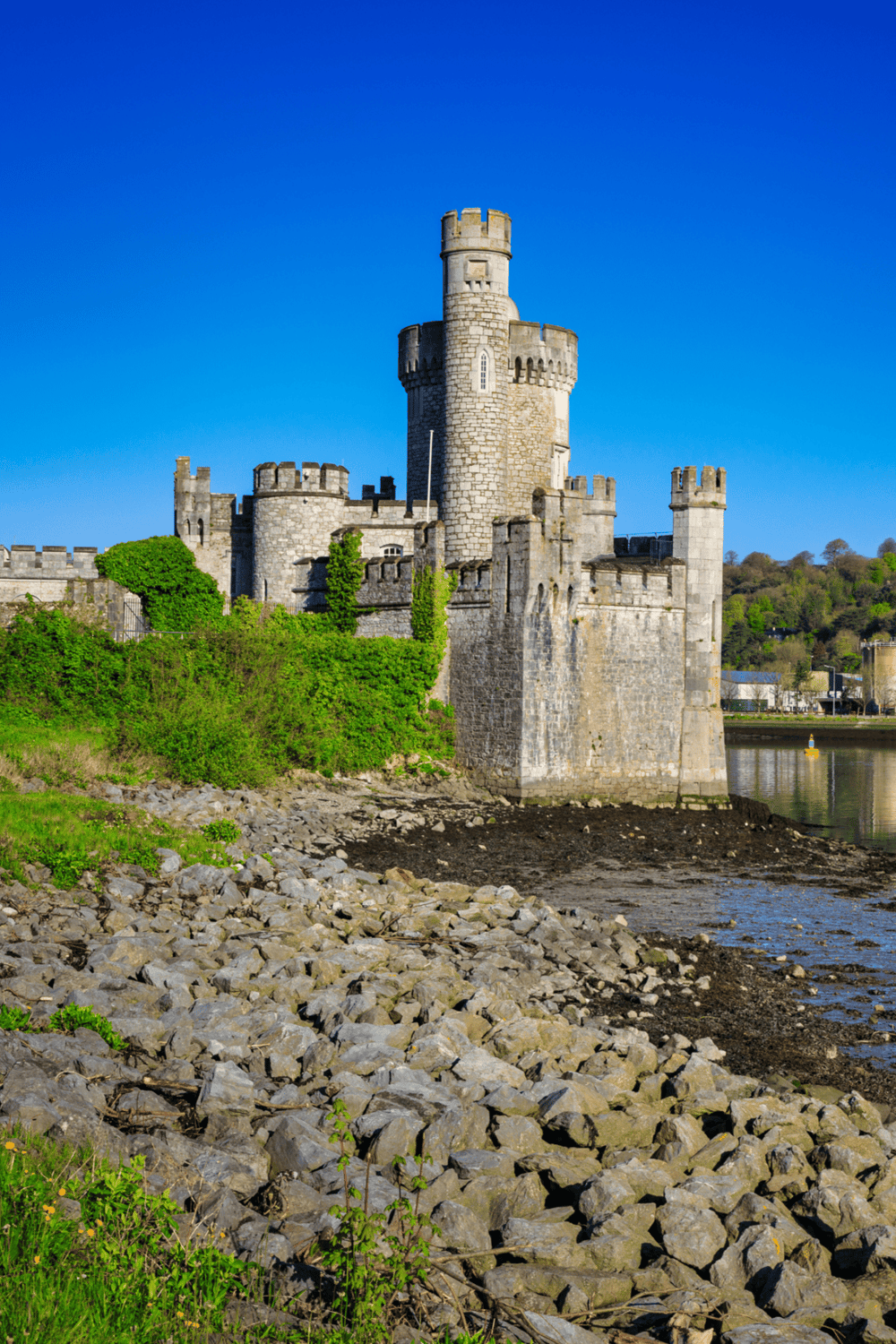 Medieval castle on riverbank with blue sky, historical architecture, tourist attraction, Scotland, QuestForDirections.