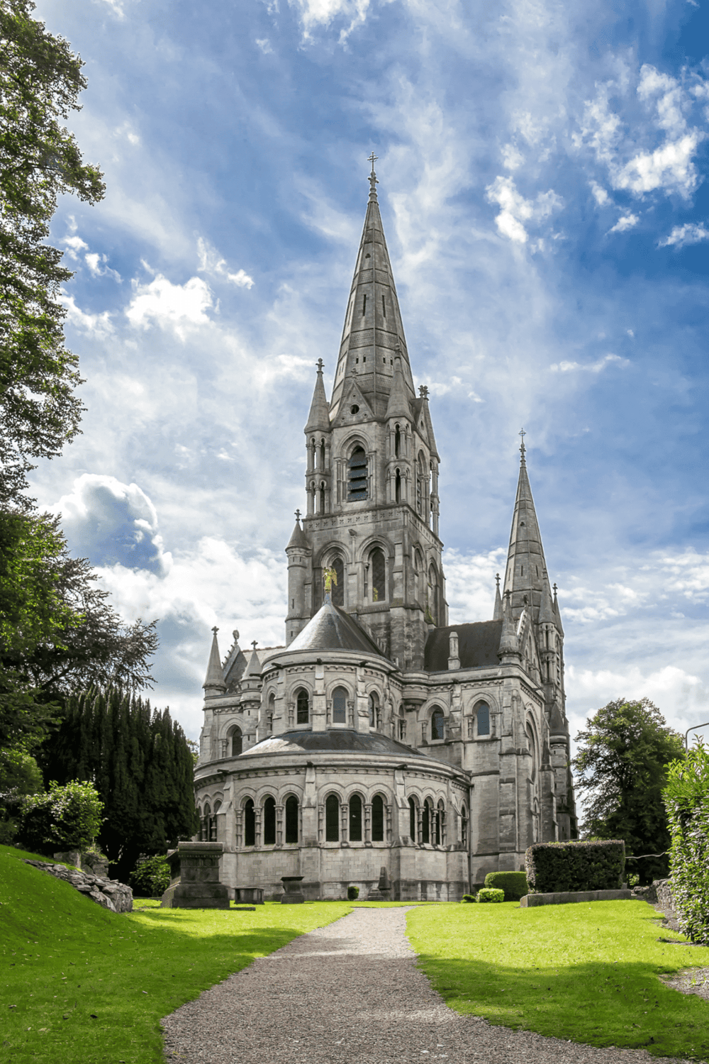 Majestic church with tall spires, historical architecture, and lush green surroundings in daylight.