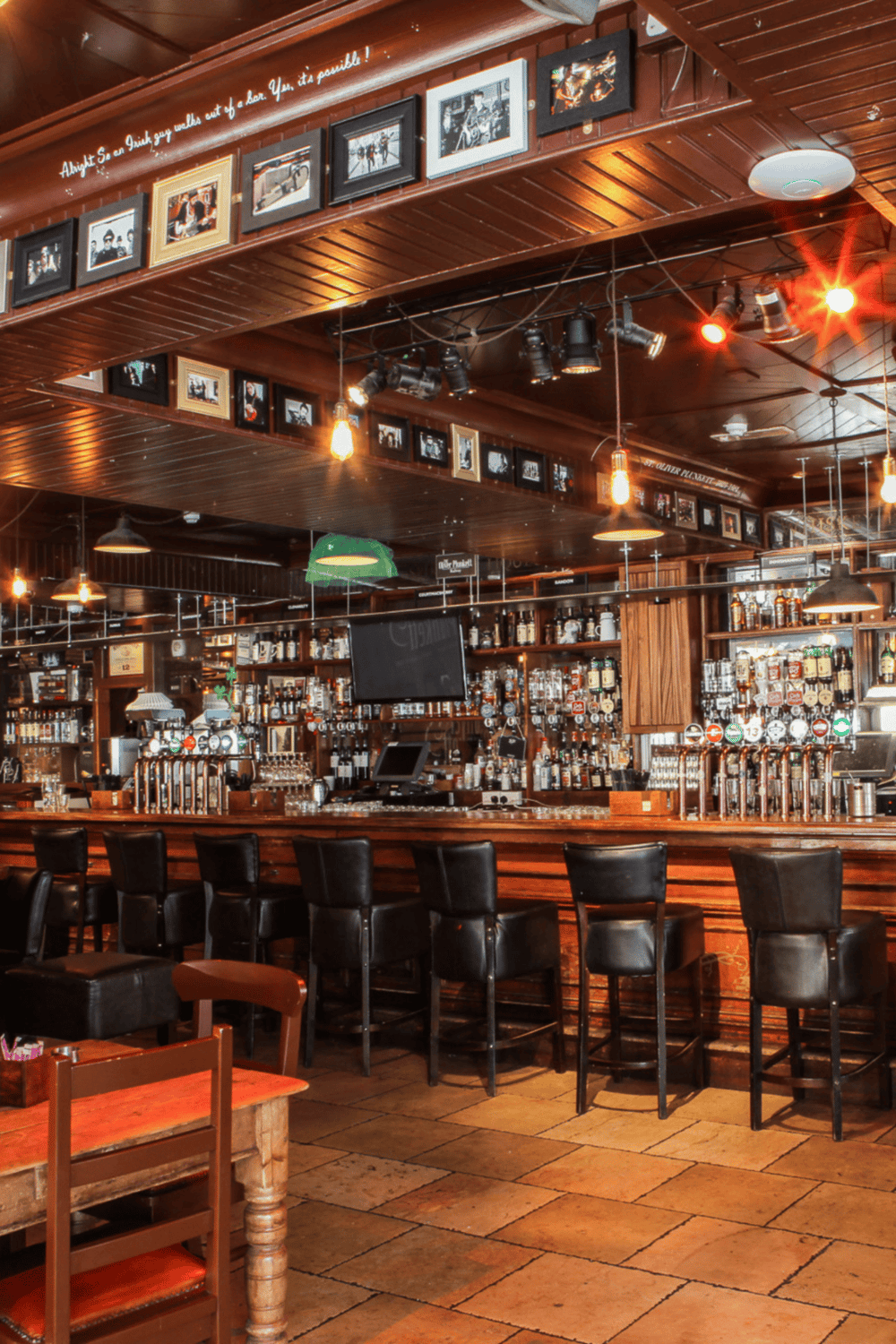 Bar interior with wooden accents and framed photos, cozy atmosphere, welcoming for socializing and drinks.