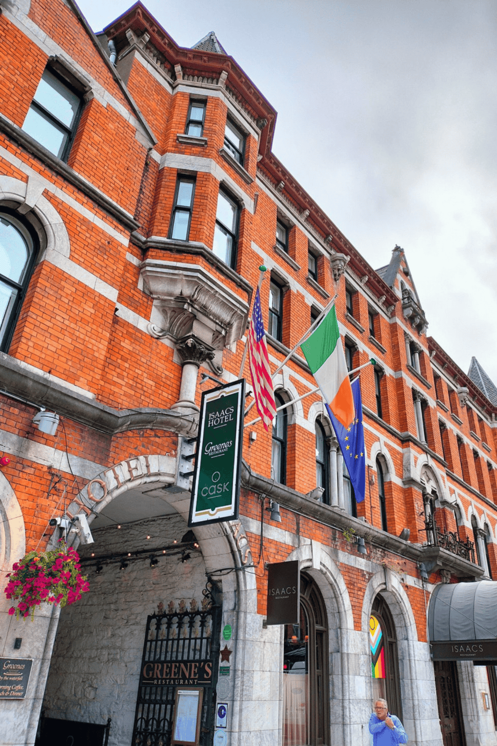 Charming historic brick hotel building with colorful flags and inviting entrance, located in a vibrant city district.