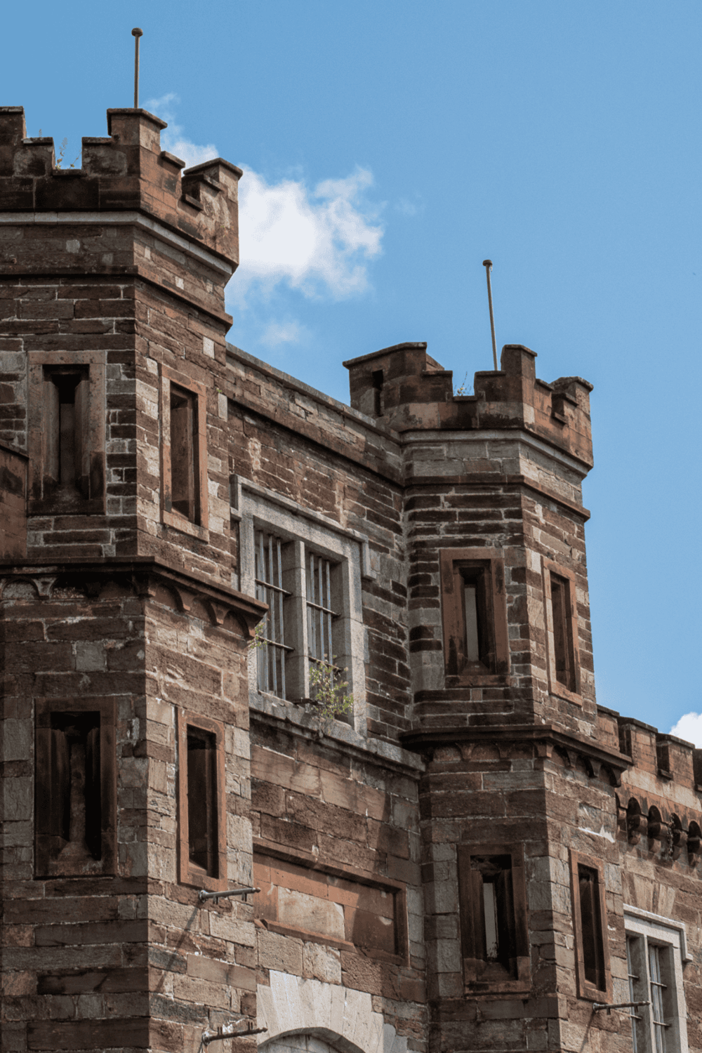 Ancient castle turret made of red sandstone with blue sky background.