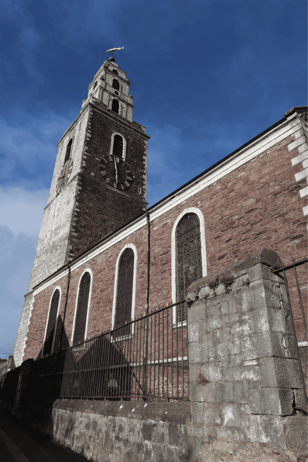 Historic church tower with clock, Gothic architecture, blue sky background.