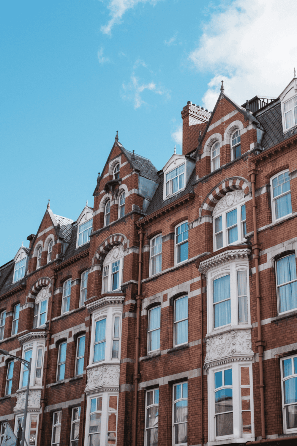 Victorian brick apartment building with ornate architectural details, under a blue sky.