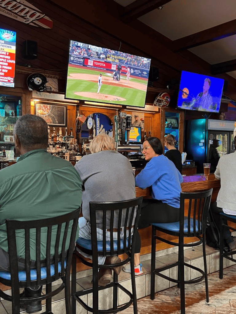 Enjoying baseball game at sports bar with multiple TVs, drinks, and social atmosphere.