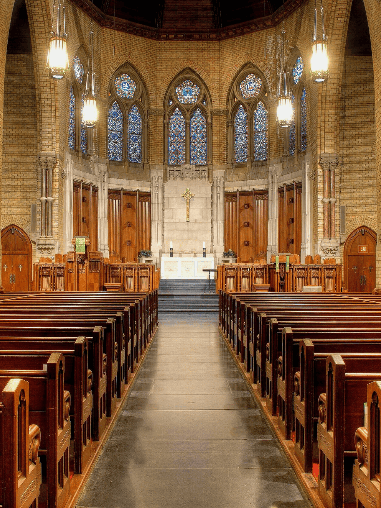 Ornate church interior with stained glass windows and wooden pews for worship.