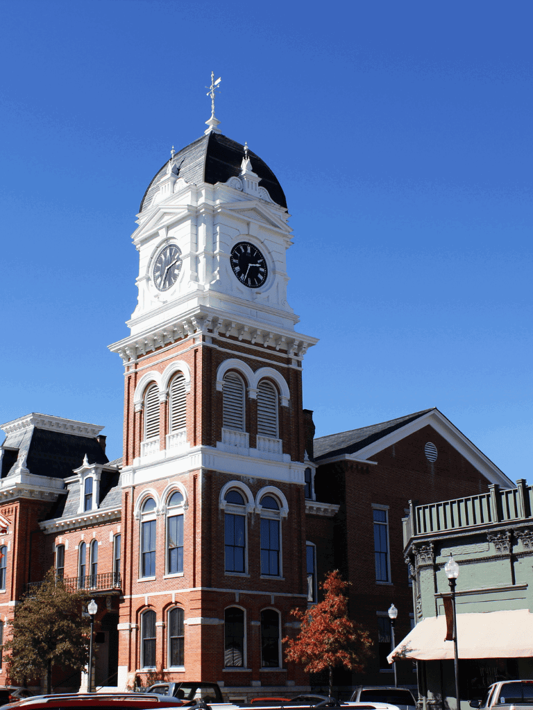 Historic courthouse clock tower with red brick architecture and blue sky background.