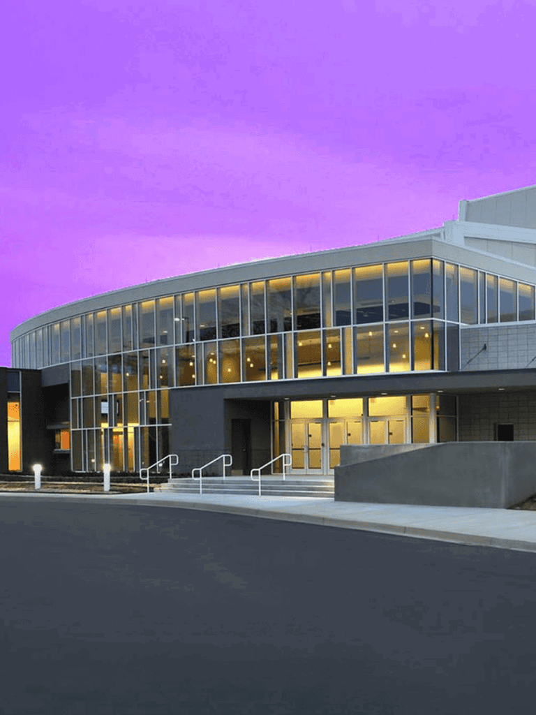 Modern QuestForDirections building with glass facade at dusk, vibrant purple sky, advanced navigation technology, and customer service focus.