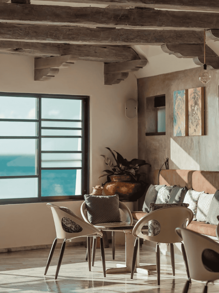 Modern coastal living room with ocean view, stylish furniture, and natural decor elements.