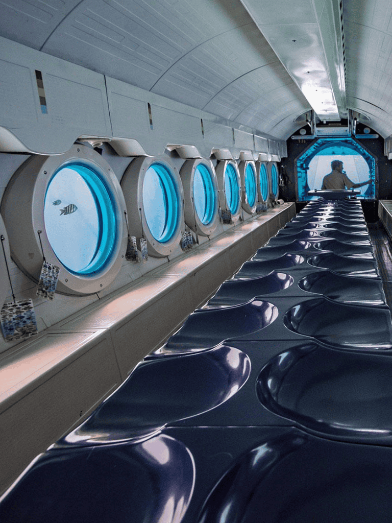 Remote underwater research station with circular observation windows and modern seating.