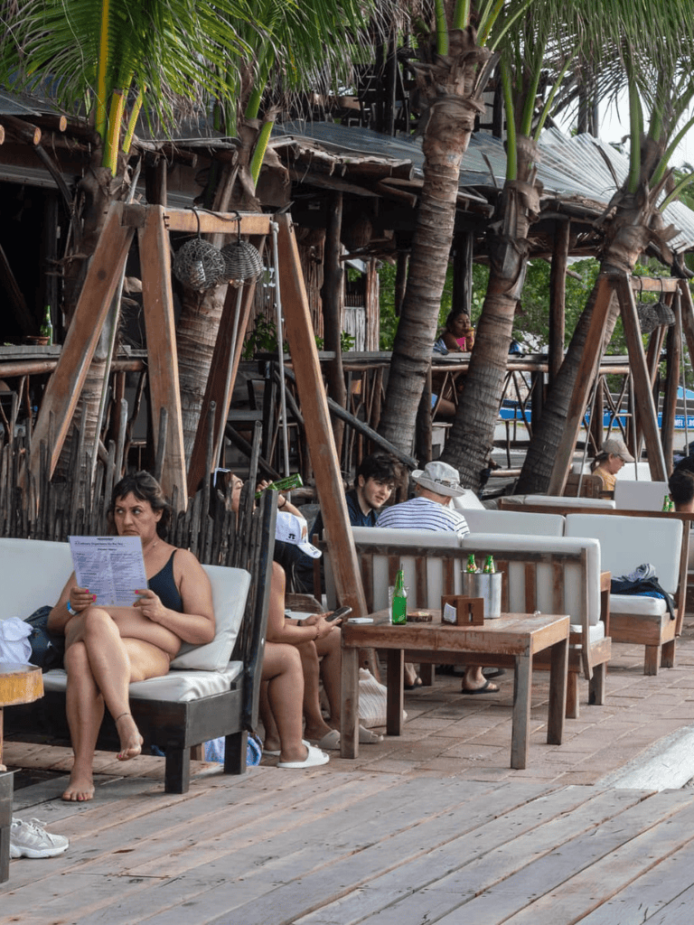 Relaxed outdoor dining area at QuestForDirections tropical resort with palm trees and seating by the water.