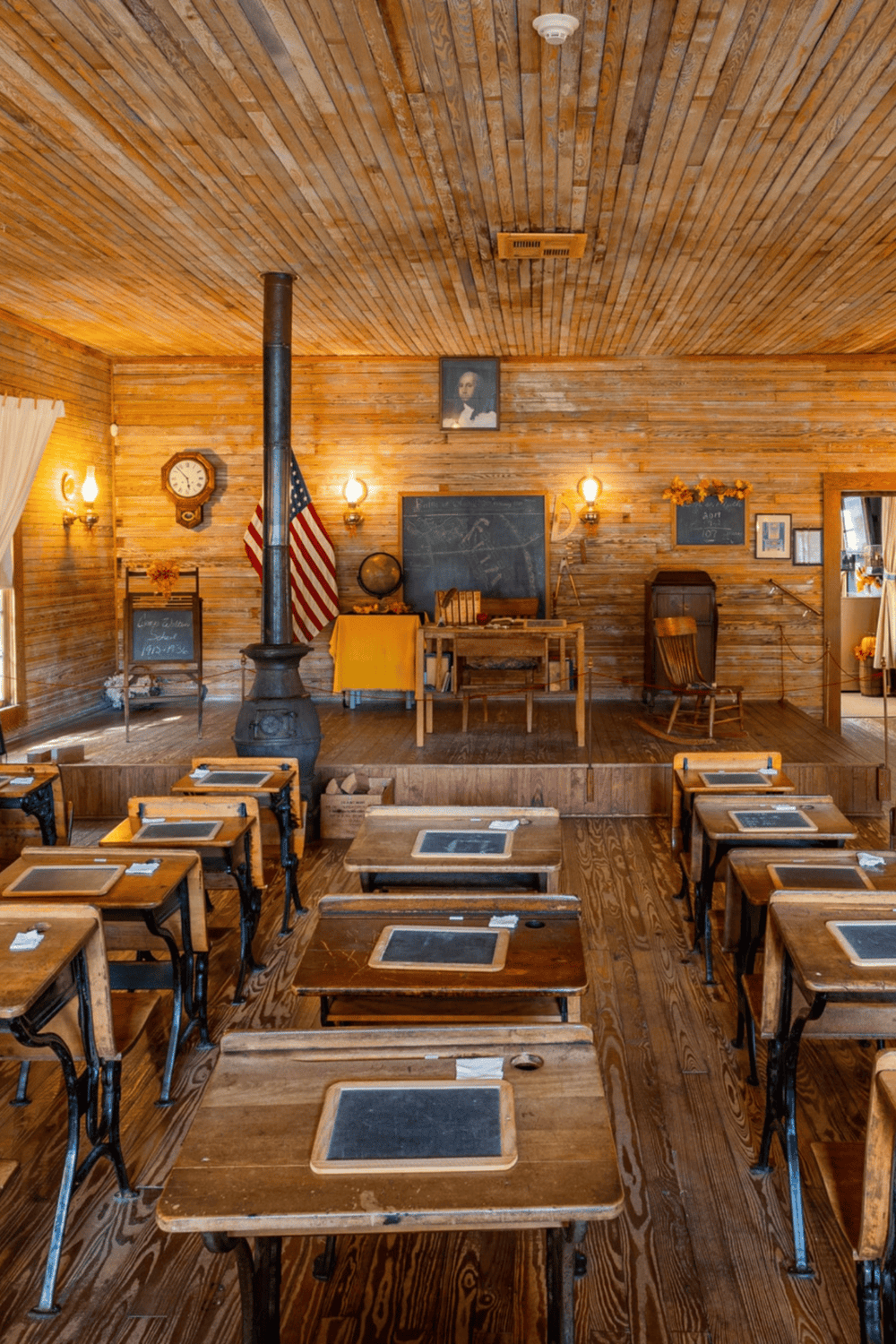 Vintage classroom with wooden desks, blackboard, and historical decorations.