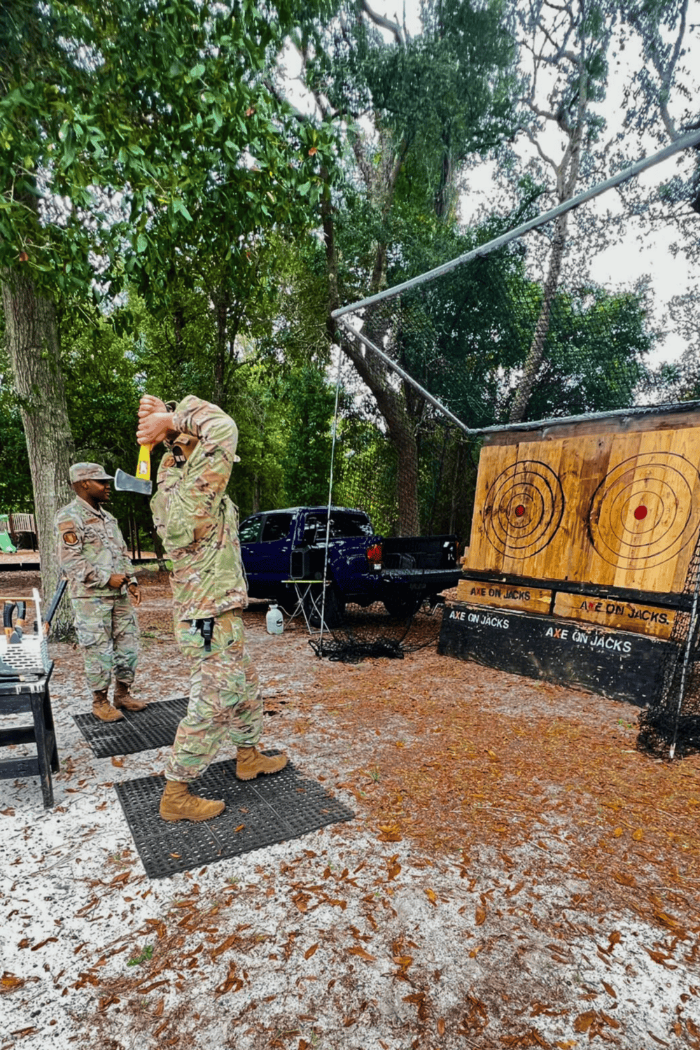1. Military personnel enjoying axe throwing outdoor activity in a wooded area.