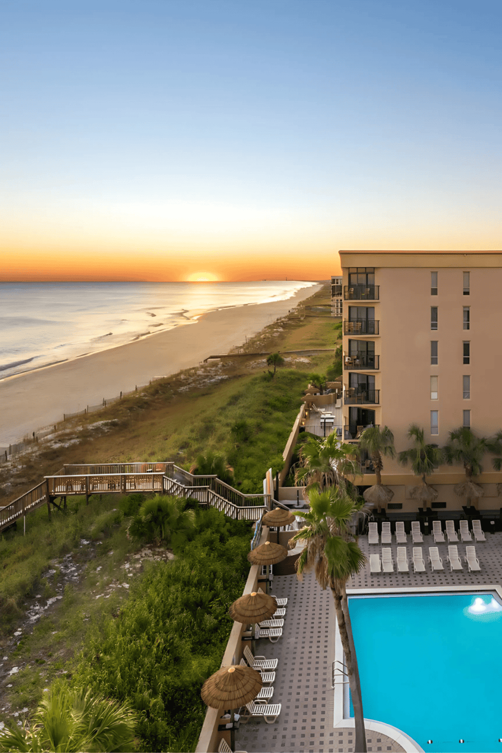 Beachside hotel ocean view sunrise with pool and lounge chairs.