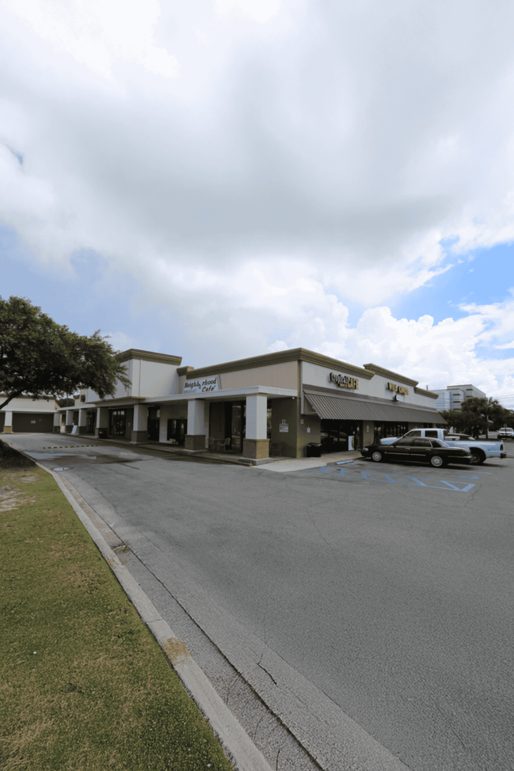 1. Large shopping center with parking lot and stores under cloudy sky.
