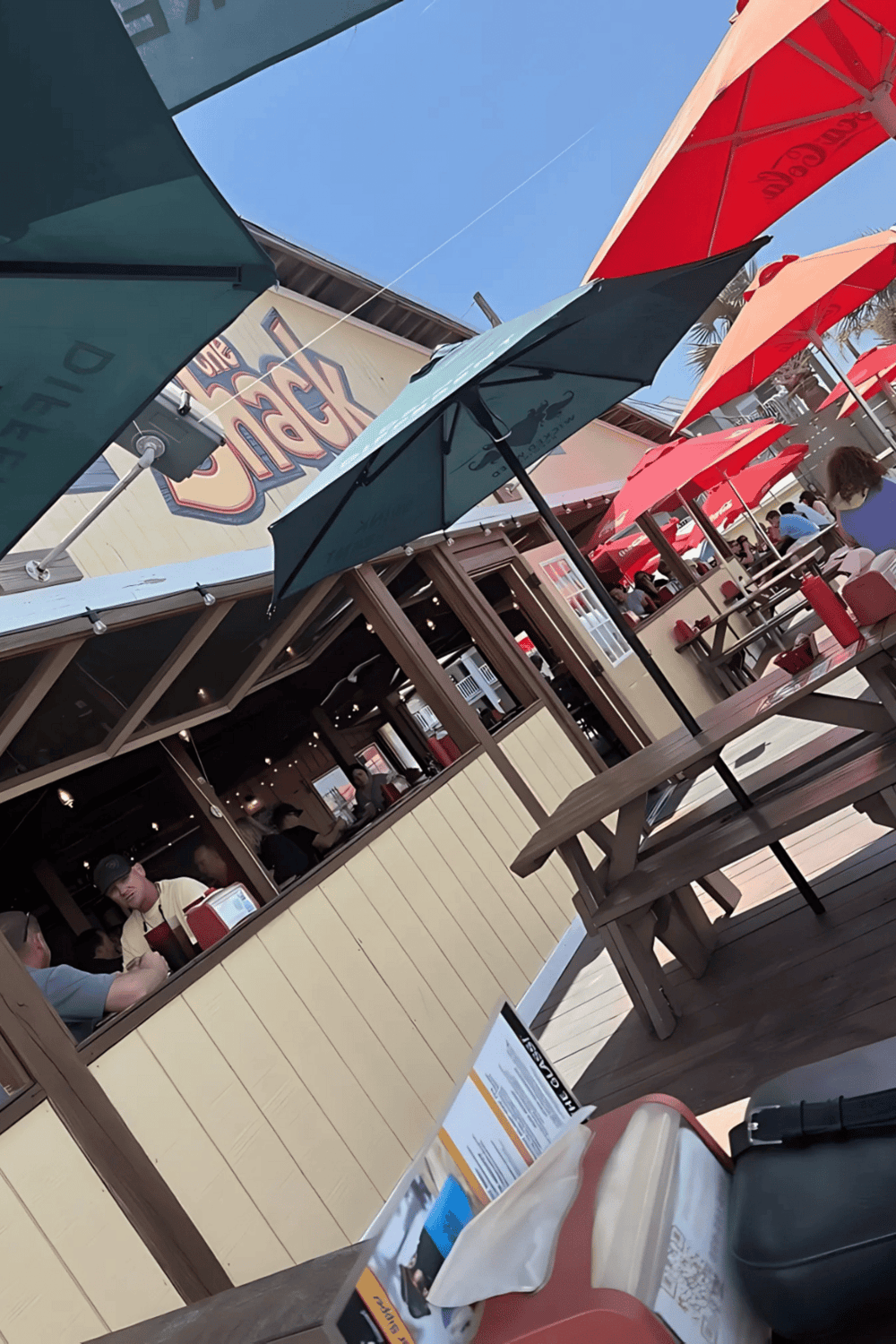 Colorful outdoor restaurant patio with umbrellas and diners, casual dining experience.