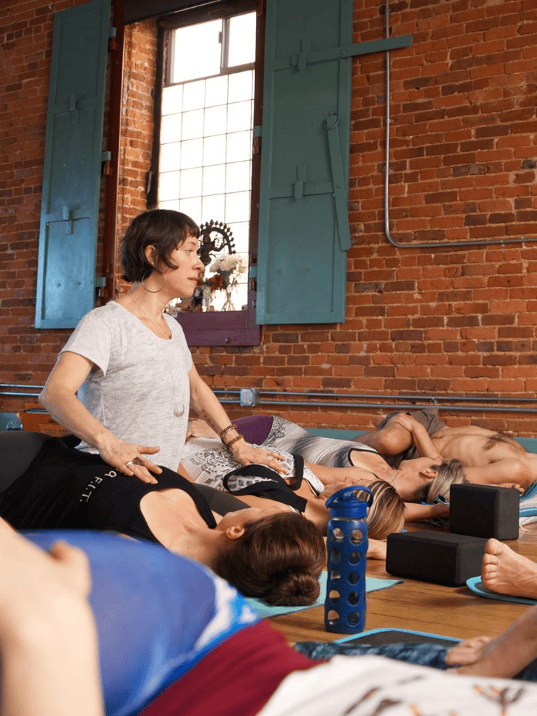 Relaxing yoga class for seniors in urban studio with brick walls and large windows.