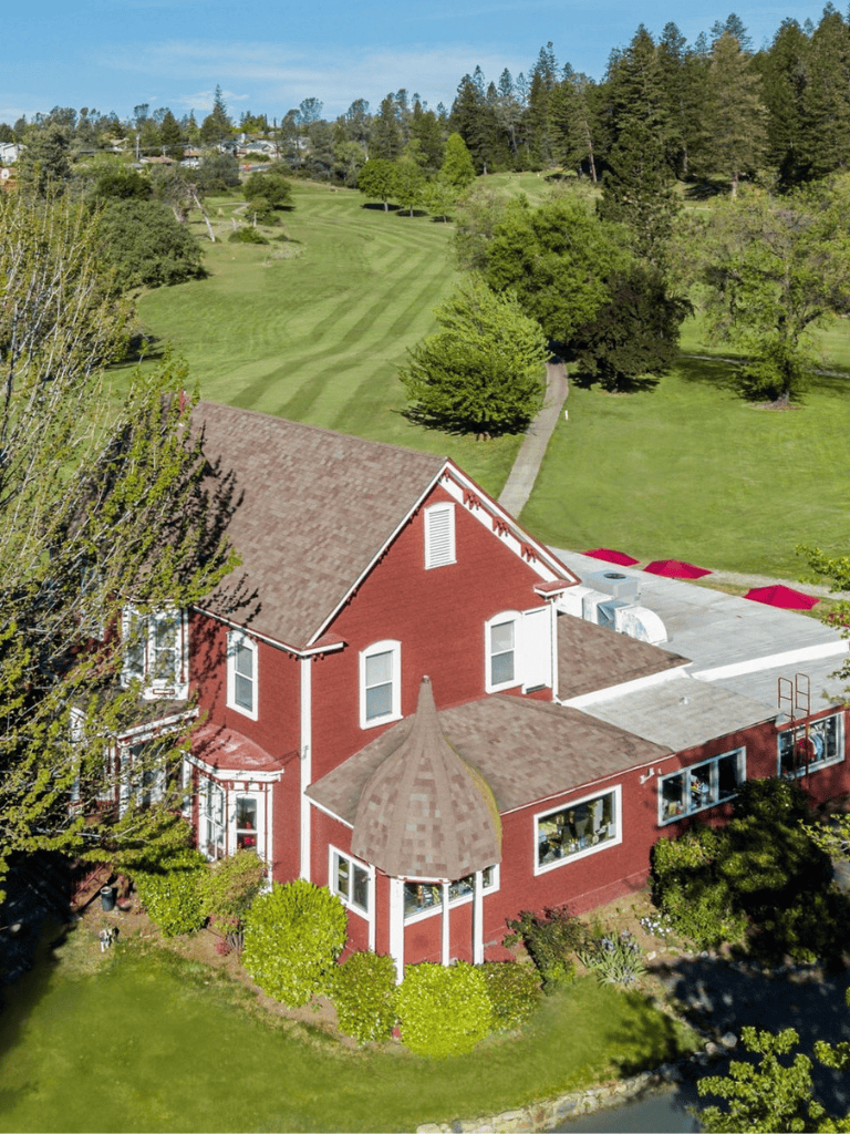 Beautiful red house with golf course views, lush landscaping, and outdoor amenities in a scenic community.