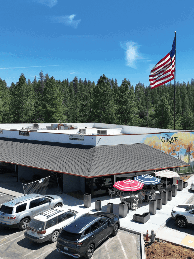 American flag flying outside a restaurant in a parking lot surrounded by trees.
