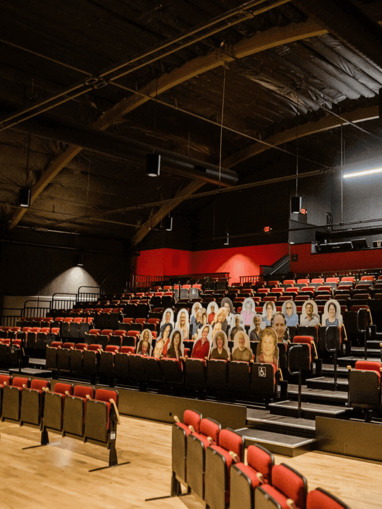 Accessible theater seating with cardboard cutouts of diverse audience members for an inclusive experience Empty auditorium seats with lifelike cardboard cutouts of diverse viewers in a modern theater setting.