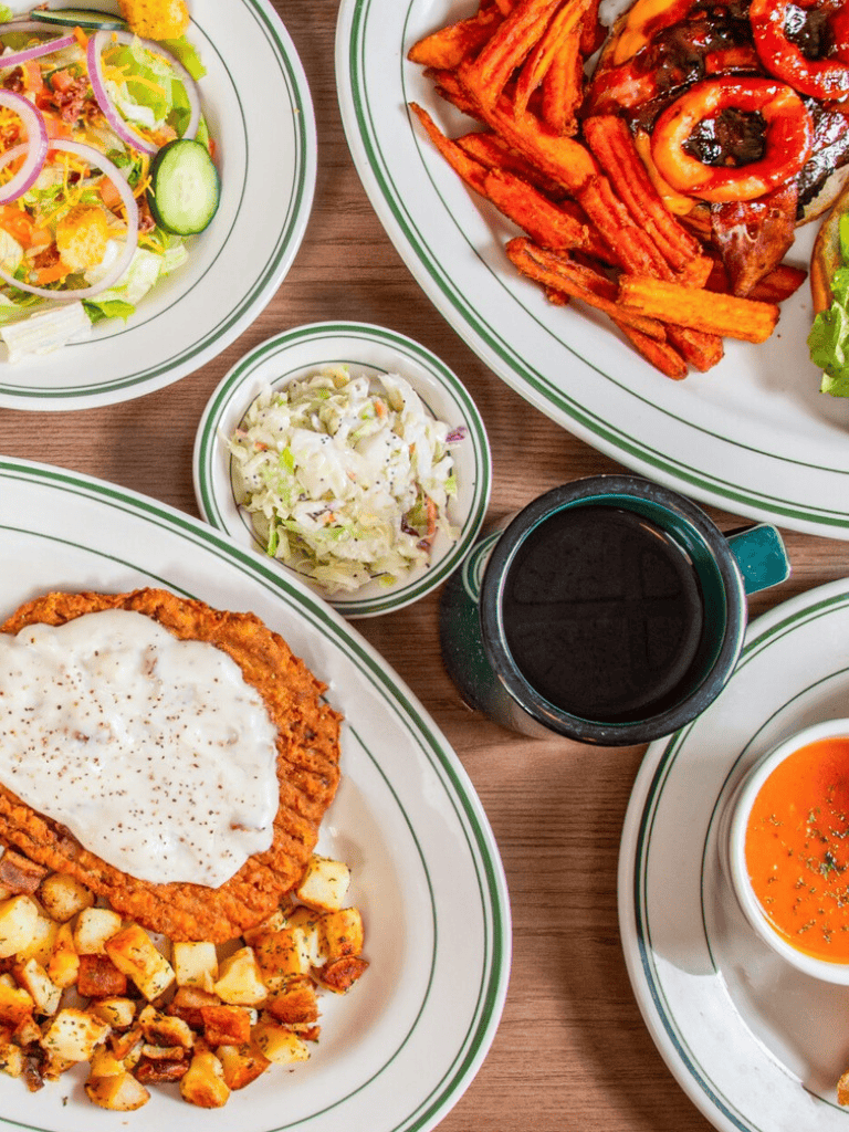 Juicy grilled chicken with creamy gravy, crispy potatoes, fresh salad, and hearty soup on a cozy dining table.