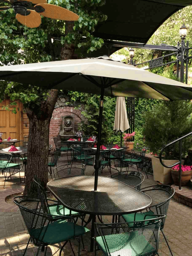 Aluminum patio table with umbrella in outdoor garden setting.