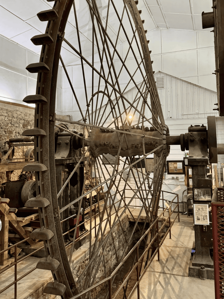 Large vintage Ferris wheel mechanism displayed in a museum setting.