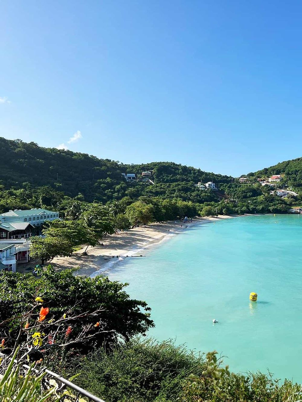 Idyllic Caribbean beach with turquoise waters and lush green hills in the background.