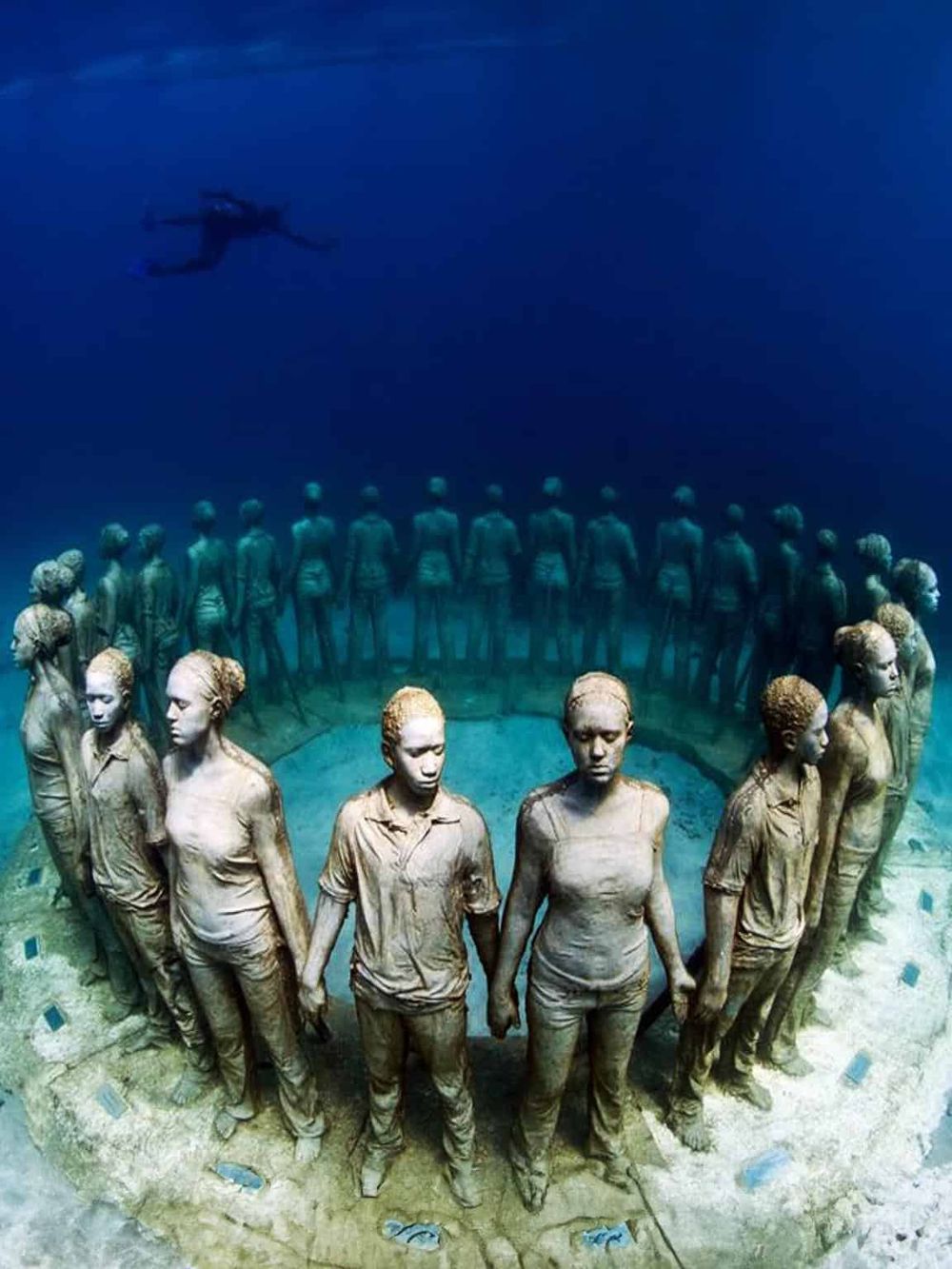 Diving sculpture of women holding hands in the ocean, symbolizing unity and human connection. Perfect for travel and cultural exploration.