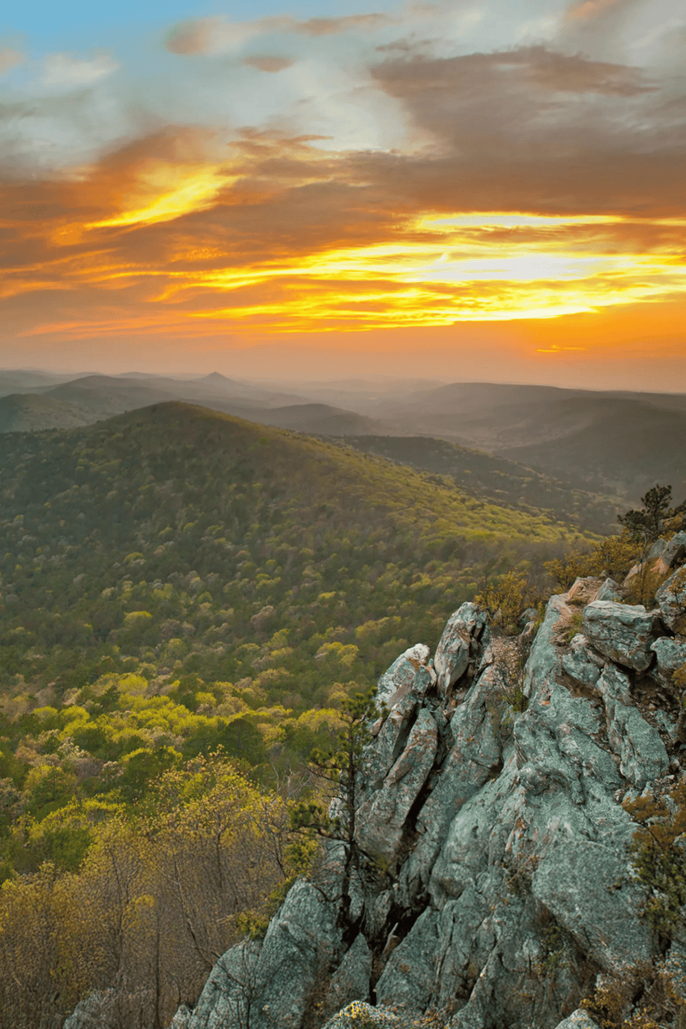 Vast mountain landscape at sunset with rocky ridge and lush green forest, scenic view from QuestForDirections.