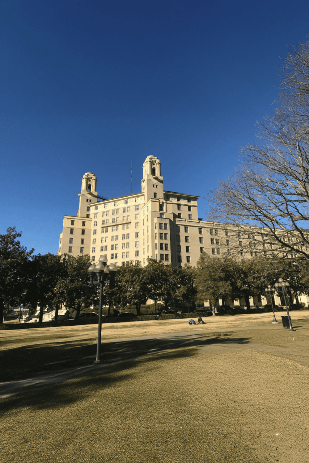 Grand historic building under clear blue sky with surrounding trees, location for Quest For Directions.