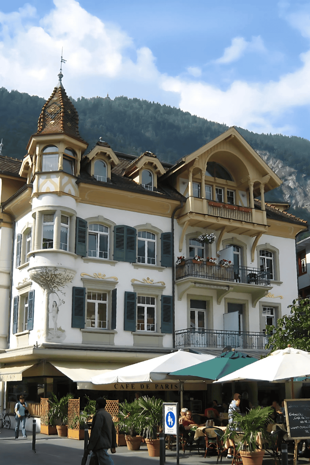 Charming European building with outdoor café in a mountain town, showcasing scenic architecture and vibrant street life.