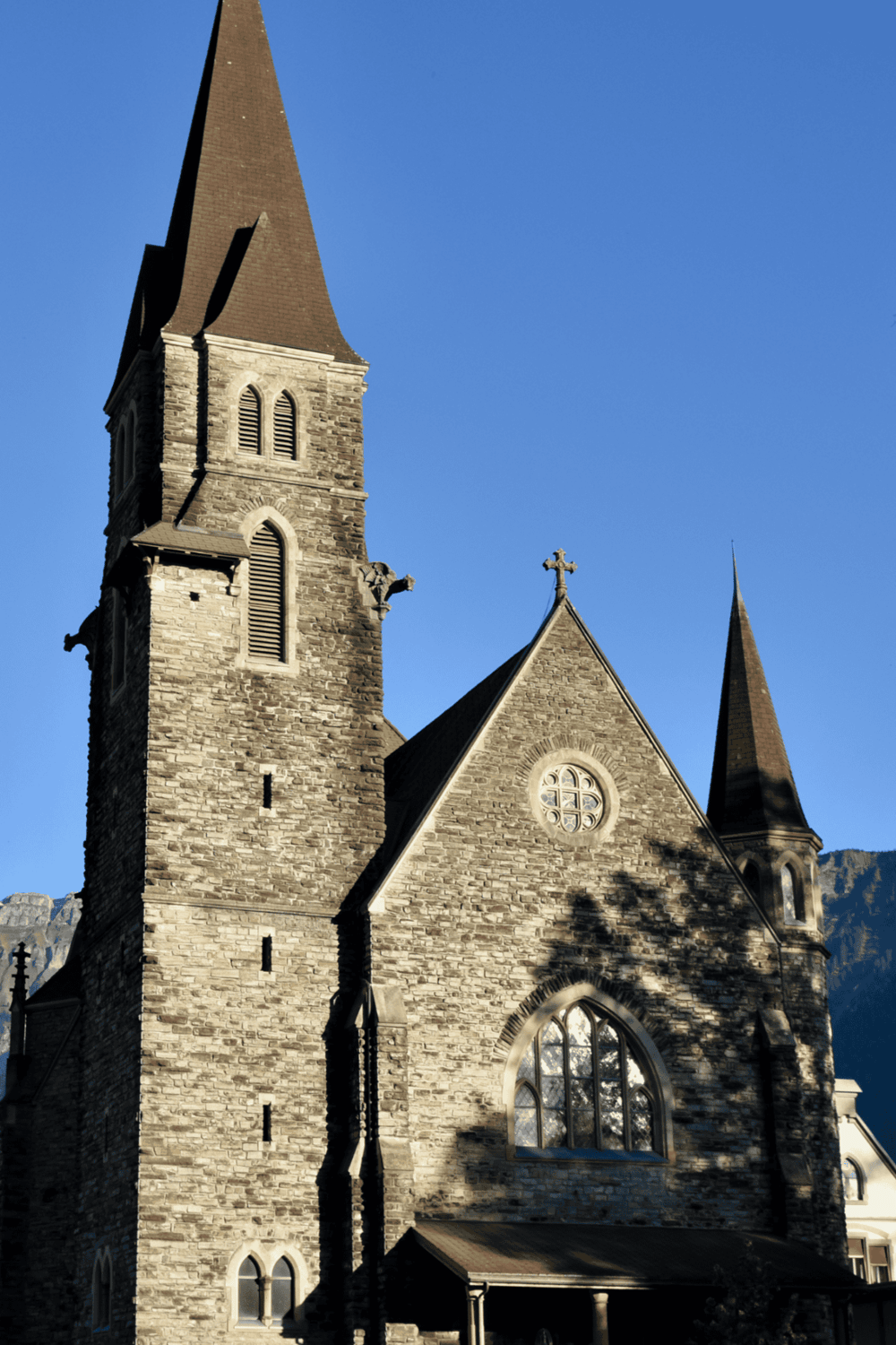 Ancient stone church with tall spires, Gothic architecture, and clear blue sky. Ideal for travel and historical sightseeing.