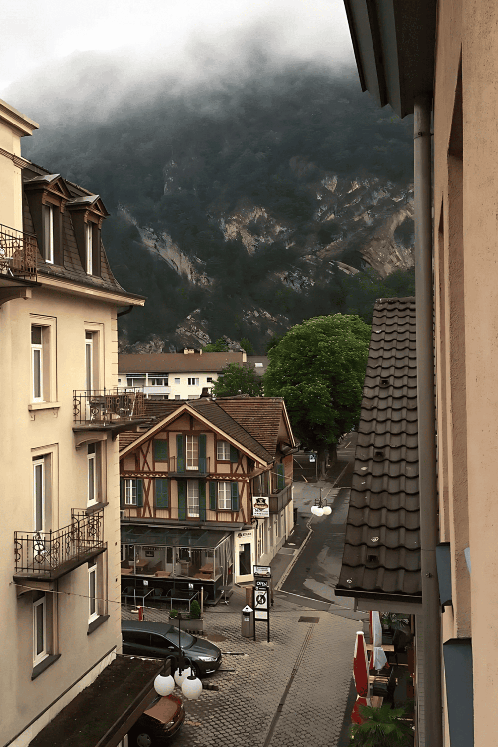 Mountain view behind buildings in a small European town, QuestForDirections.
