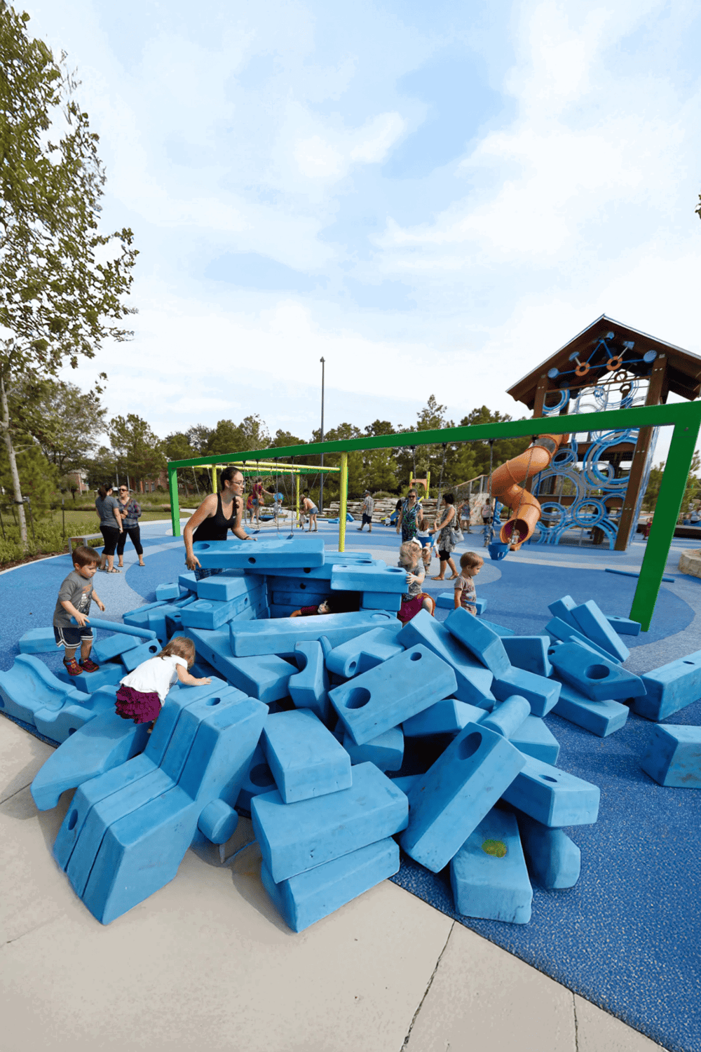 Bright children’s playground with blue climbing blocks and swings, perfect for family fun and outdoor activities.