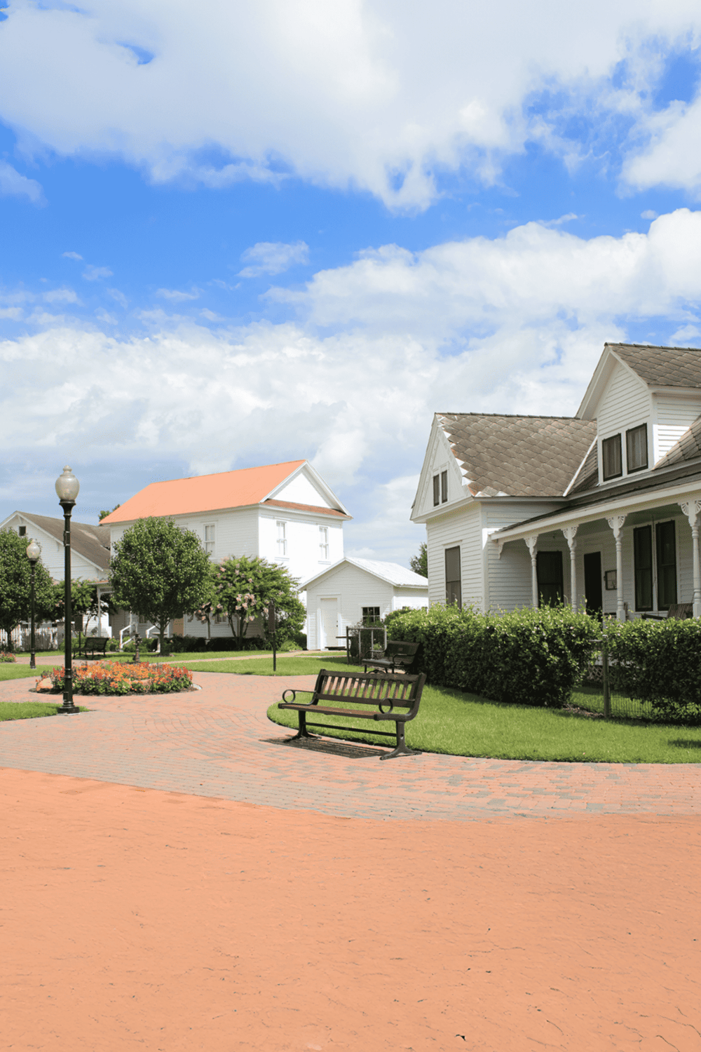 Peaceful neighborhood street with white houses, trees, and blue sky, ideal for neighborhood navigation and directions.