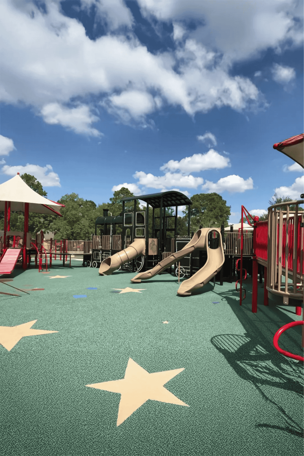 Colorful playground with slides, climbing structures, and star-shaped patterns on soft rubber flooring. Ideal for children's outdoor recreation.