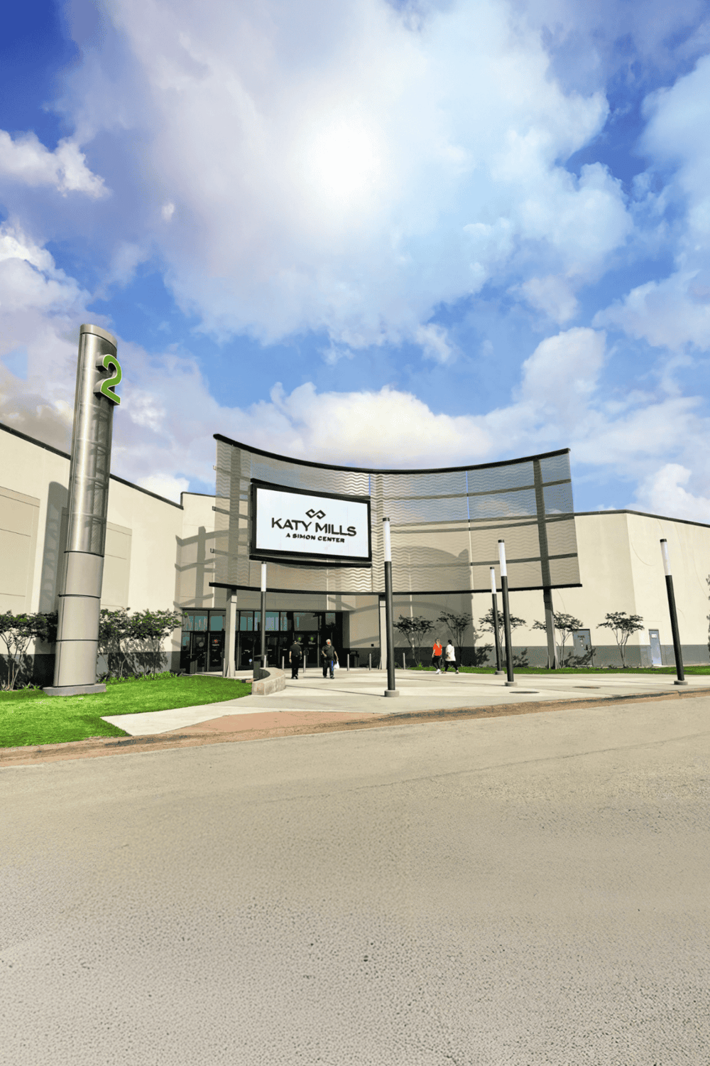 Shopping mall entrance with Katy Mills sign, modern architecture, and blue sky with clouds, ideal for retail exploration and directions.