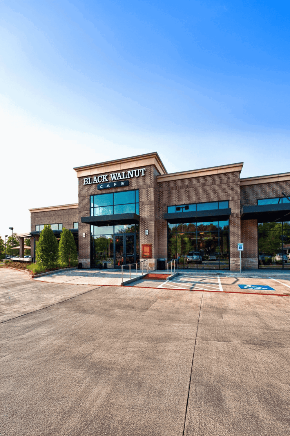 Bright exterior of Black Walnut Café in a modern shopping center, with accessible parking spaces and clear signage.
