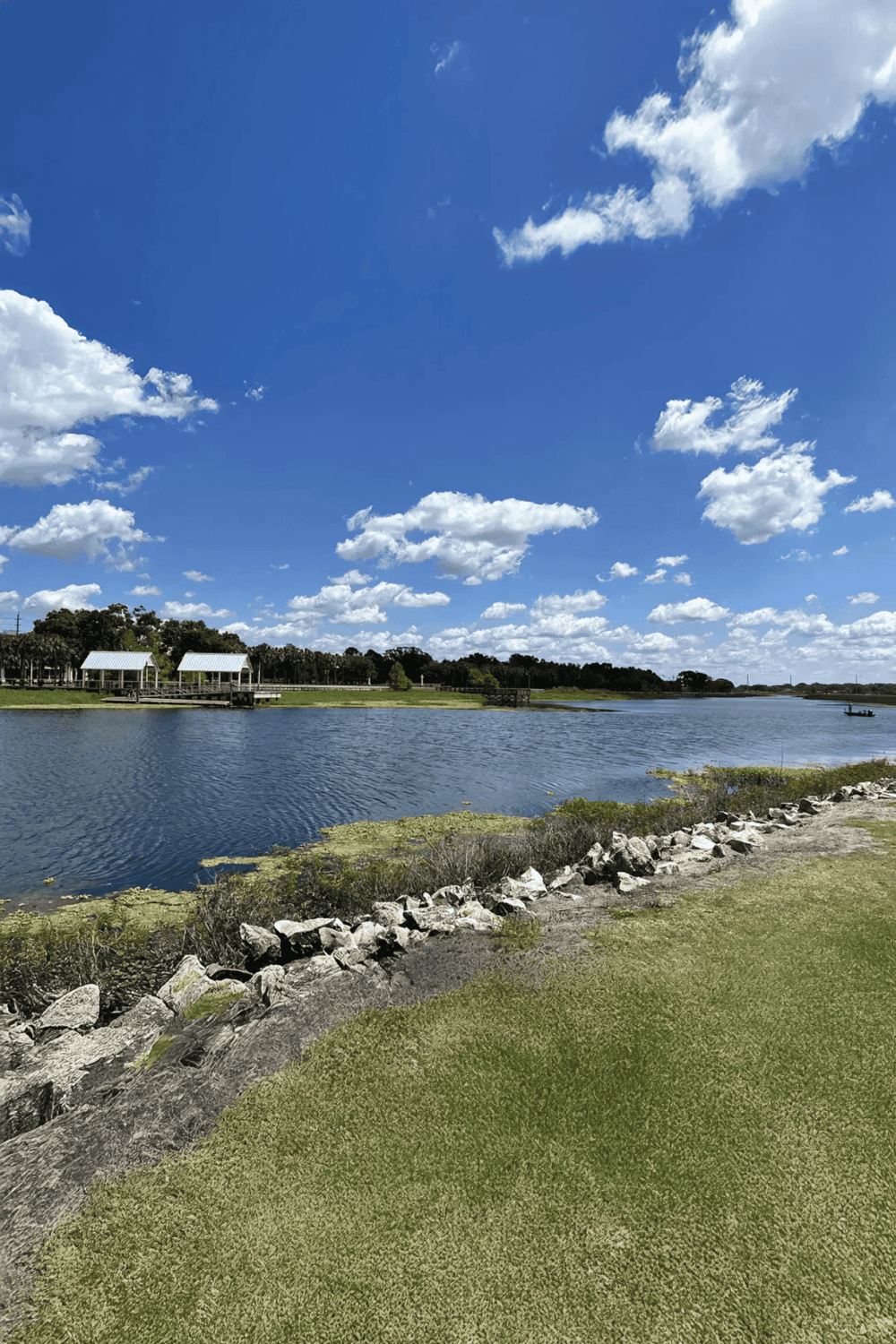 Relaxing lakeside scenery with sky, clouds, and grassy bank for outdoor activities.