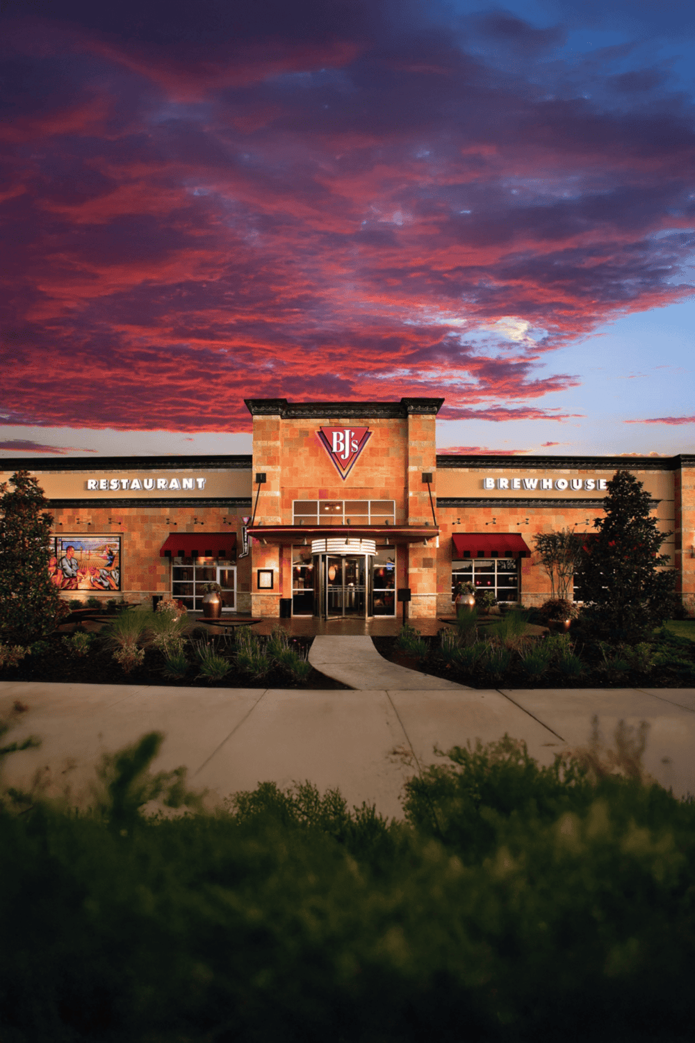 Chick-fil-A restaurant during sunset with vibrant sky, inviting atmosphere, corner entrance, and well-maintained landscaping.