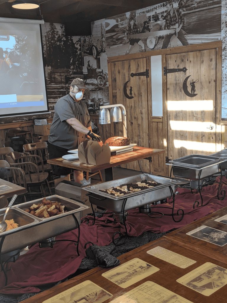 Roast beef carving station at a rustic restaurant with vintage decor and outdoor-themed wall art.