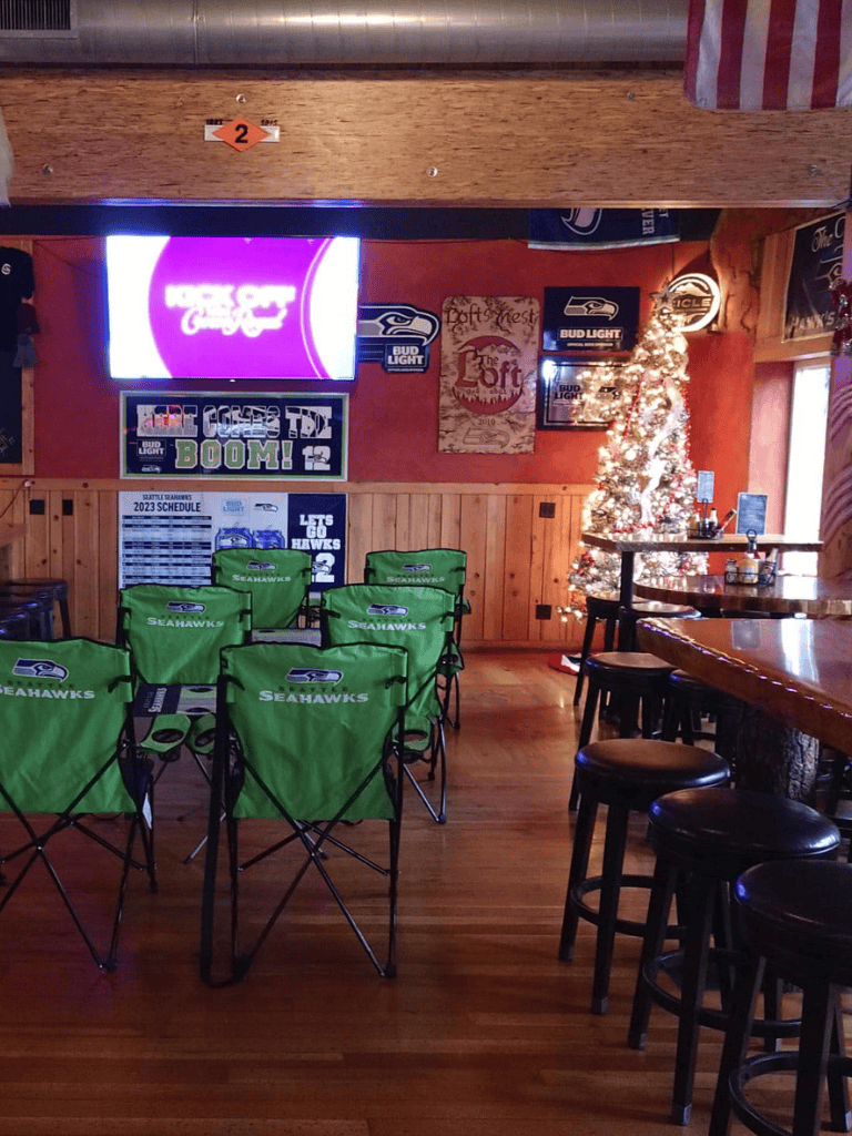 Seahawks-themed bar with sports decor, Christmas tree, and TV screens at QuestForDirections.