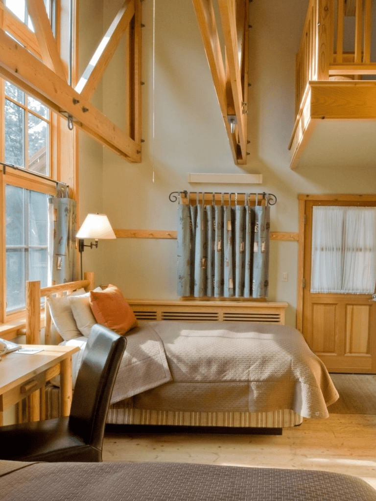 Cozy rustic bedroom with natural wood accents, large windows, and loft area at QuestForDirections.